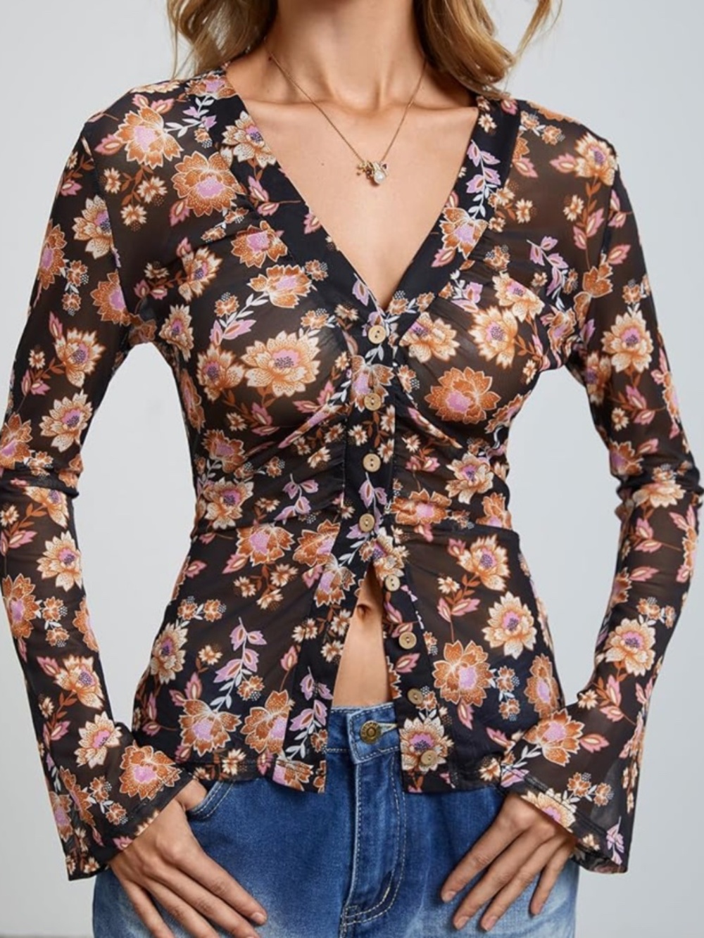 Sheer black long-sleeve top with an all-over floral print. Button-front design f
